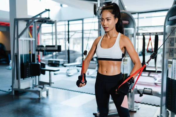 Young Asia lady exercise doing exercise-machine Cable Crossover fat burning workout in fitness class. Athlete with six pack, Sportswoman recreational activity, functional training, healthy lifestyle.