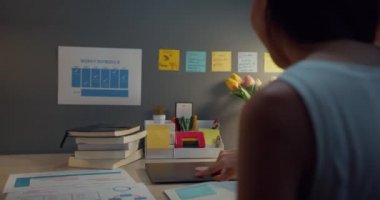 Genç Asyalı iş kadını serbest bilgisayar uzmanı ev gecesinde oturma odasındaki ahşap masa üzerinde çalışmaya başlamak için hazırlanıyor. Evden çalış, uzaktan, koronavirüs için karantina.