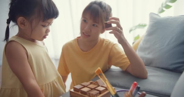 快乐快乐的亚洲家庭妈妈在家里客厅的沙发上用木盒教女孩玩棋盘游戏 在一起的时间 社会距离 — 图库视频影像