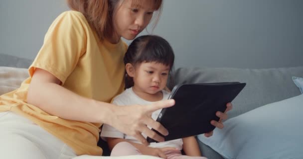 즐거운 아시아의 엄마와 귀여운 아이가 디지탈 태블릿 만화를 사용하고 거실의 — 비디오