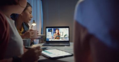 Laptop kullanan Asyalı iş kadınları iş arkadaşlarıyla evdeki video görüşme planlarını konuşuyorlar. Geceleri ev aşırı yükleme, uzaktan çalışma, sosyal uzaklık, koronavirüs için karantina.