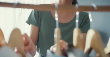 Yakından bakınca çekici Asyalı kadın elbise askısından elbise seçiyor. Oturma odasındaki aynada kendine bakıyor. Kız ne giyeceğini düşünüyor. Yaşam tarzı kadınları ev kavramında rahatlar.