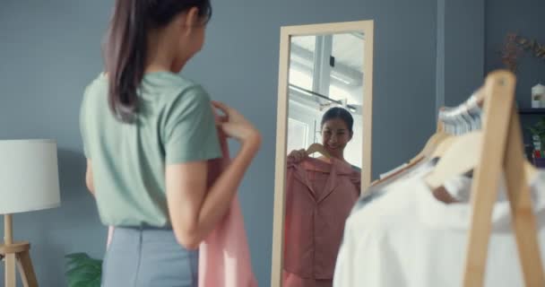 Schöne Attraktive Asiatin Die Kleider Auf Kleiderständern Auswählt Und Sich — Stockvideo