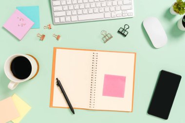 Çalışma masasının yaratıcı düz yatay fotoğrafı. Klavyesi, faresi ve pastel yeşil arka planda açık siyah defteri olan üst görünüm ofis masası. Üst görünüm, fotokopi alanı fotoğrafçılığıyla aynı..