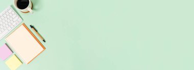 Çalışma masasının yaratıcı düz yatay fotoğrafı. Klavyeli en üst ofis masası ve pastel yeşil arka planda açık siyah defter. Üst görünüm, fotokopi alanı fotoğrafçılığıyla aynı..