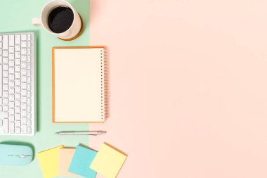 Çalışma masasının yaratıcı düz yatay fotoğrafı. Üzerinde klavye, fare ve açık maket siyah defter olan en iyi ofis masası. Pastel yeşil pembe arka planda. Üst görünüm, fotokopi alanı fotoğrafçılığıyla aynı..