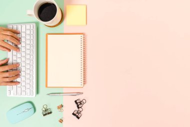 Çalışma masasının yaratıcı düz yatay fotoğrafı. Üzerinde klavye, fare ve açık maket siyah defter olan en iyi ofis masası. Pastel yeşil pembe arka planda. Üst görünüm, fotokopi alanı fotoğrafçılığıyla aynı..