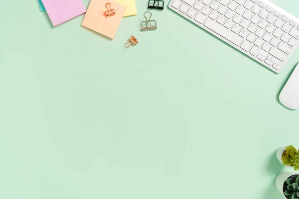 Minimal work space - Creative flat lay photo of workspace desk. Top view office desk with keyboard, mouse and book on pastel green color background. Top view with copy space, flat lay photography.