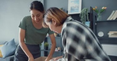 Güzel Asya çifti bayan boks yapmaktan mutlu ve evdeki oturma odasındaki çevrimiçi kıyafet ürünlerinin kalitesini denemekten ve eşleştirmekten zevk alıyor. Çevrimiçi alışveriş ve dağıtım kavramı.