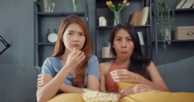 Çekici Asya çifti, neşeli, gündelik hayattan memnuniyet duyan güzel bayan. Keyfinize bakın ve evdeki oturma odasındaki kanepede online film eğlencesi izleyin. Yaşam tarzı aktivite karantina konsepti.