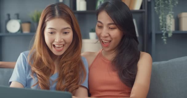 Две Азиатские Лесбиянки Сайт Диване Вместе Глядя Экран Ноутбука Гостиной — стоковое видео