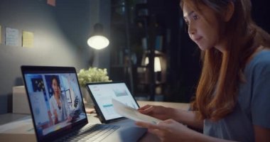 Dizüstü bilgisayar kullanan Asyalı kadın, evdeki oturma odasında çalışırken iş hakkında iş arkadaşlarıyla konuşuyor. Kişisel izolasyon, sosyal uzaklık, koronavirüsü önlemek için karantina.