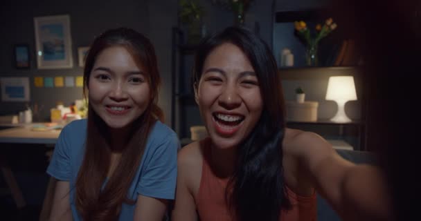 年轻的亚洲女人开心地微笑着 晚上在客厅里放松地看着相机 快乐的室友女士与朋友和家人视频通话 家庭妇女的生活方式理念 — 图库视频影像