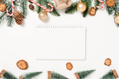 Kış, geleneksel Noel kompozisyonu ve yeni yıl tatili sezonunun en az yaratıcı düzlüğü. Üst görünüm beyaz arkaplandaki metin için siyah defteri aç. Model yap ve uzay fotoğrafçılığını kopyala.