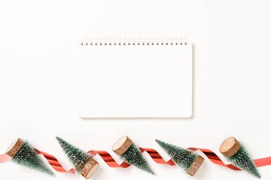 Kış, geleneksel Noel kompozisyonu ve yeni yıl tatili sezonunun en az yaratıcı düzlüğü. Üst görünüm beyaz arkaplandaki metin için siyah defteri aç. Model yap ve uzay fotoğrafçılığını kopyala.