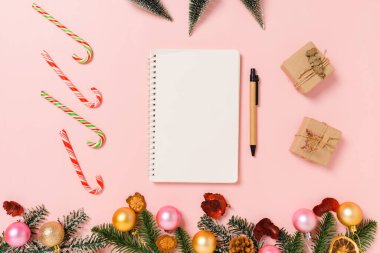 Kış, geleneksel Noel kompozisyonu ve yeni yıl tatili sezonunun en az yaratıcı düzlüğü. Üst görünüm, pembe arkaplandaki metin için siyah defter. Model yap ve uzay fotoğrafçılığını kopyala.