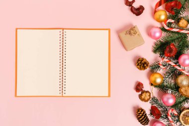 Kış, geleneksel Noel kompozisyonu ve yeni yıl tatili sezonunun en az yaratıcı düzlüğü. Üst görünüm, pembe arkaplandaki metin için siyah defter. Model yap ve uzay fotoğrafçılığını kopyala.