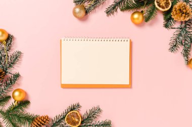 Kış, geleneksel Noel kompozisyonu ve yeni yıl tatili sezonunun en az yaratıcı düzlüğü. Üst görünüm, pembe arkaplandaki metin için siyah defter. Model yap ve uzay fotoğrafçılığını kopyala.