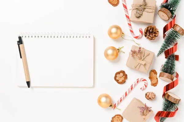 Kış, geleneksel Noel kompozisyonu ve yeni yıl tatili sezonunun en az yaratıcı düzlüğü. Üst görünüm beyaz arkaplandaki metin için siyah defteri aç. Model yap ve uzay fotoğrafçılığını kopyala.