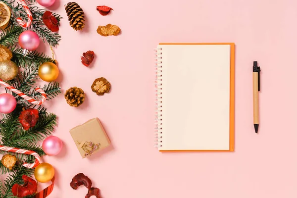 Kış, geleneksel Noel kompozisyonu ve yeni yıl tatili sezonunun en az yaratıcı düzlüğü. Üst görünüm, pembe arkaplandaki metin için siyah defter. Model yap ve uzay fotoğrafçılığını kopyala.