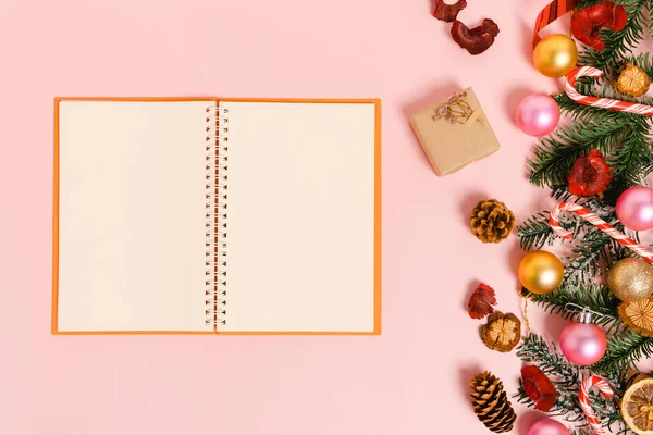 Kış, geleneksel Noel kompozisyonu ve yeni yıl tatili sezonunun en az yaratıcı düzlüğü. Üst görünüm, pembe arkaplandaki metin için siyah defter. Model yap ve uzay fotoğrafçılığını kopyala.