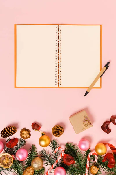 Kış, geleneksel Noel kompozisyonu ve yeni yıl tatili sezonunun en az yaratıcı düzlüğü. Üst görünüm, pembe arkaplandaki metin için siyah defter. Model yap ve uzay fotoğrafçılığını kopyala.