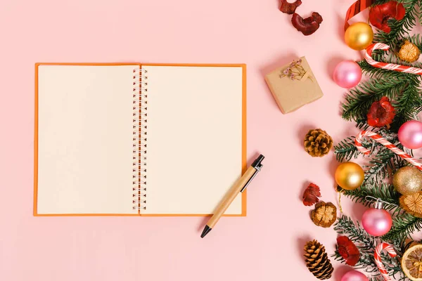 Kış, geleneksel Noel kompozisyonu ve yeni yıl tatili sezonunun en az yaratıcı düzlüğü. Üst görünüm, pembe arkaplandaki metin için siyah defter. Model yap ve uzay fotoğrafçılığını kopyala.