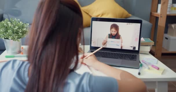 年轻的亚洲女孩带着随意使用的电脑笔记本电脑视频电话在网上学习 老师在家里写笔记本客厅 隔离教育在线电子学习验尸官流行病概念 — 图库视频影像