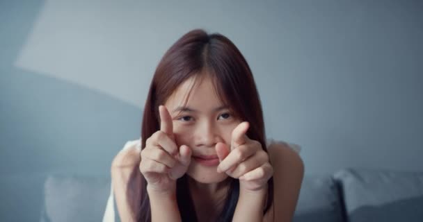 快乐的亚洲少女 带着滑稽的瞬间 在客厅里看着相机 做出滑稽而愚蠢的表情 隔离活动生活方式 社会距离大肠癌流行概念 — 图库视频影像