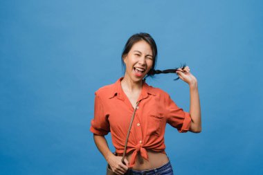 Olumlu ifadeli genç Asyalı bayan, geniş bir gülümseme, günlük kıyafetler giymiş ve mavi arka plandan kameraya bakıyor. Mutlu, sevimli, mutlu kadın başarıya sevinir. Yüz ifadesi kavramı.