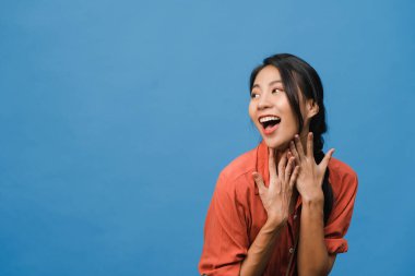 Genç Asyalı bayan mutluluğu olumlu bir ifadeyle hissediyor, neşeli sürpriz funky, mavi arka planda izole edilmiş günlük giysiler içinde. Mutlu, sevimli, mutlu kadın başarıya sevinir. Yüz ifadesi.