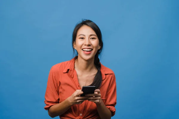 Overrasket Ung Asiatisk Dame Som Bruker Mobiltelefon Med Positivt Uttrykk stockbilde