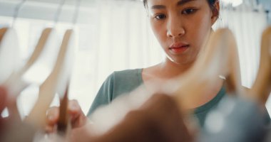 Güzel, çekici, genç Asyalı bayan elbise seçimini evdeki ya da mağazadaki dolapta yapıyor. Kız ne giyeceğini düşünüyor. Evde gardırop ya da giyim mağazası soyunma odası.