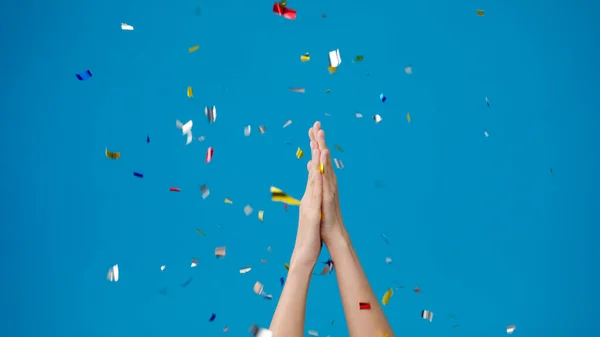 Young girl show hand clapping applause under confetti rain and celebrating over blue background. Copy space for place a text, message for advertisement. Advertising area, mock up promotional content.