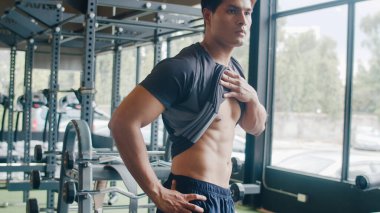 Yakışıklı Asyalı adam çıplak bedenini çıkarıp kaslarına bakıyor ve aynada vücut geliştirme eğitimi alıyor. Vücut geliştiren erkek modeller, spor, spor ve sağlıklı yaşam tarzı konsepti.