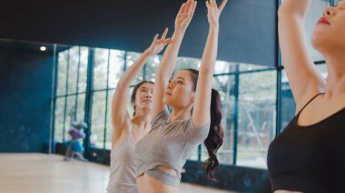 Genç Asyalı sportif çekici insanlar eğitmenle yoga dersi alıyor. Fitness stüdyosunda sağlıklı yaşam tarzı uygulayan Asya 'lı bir grup kadın. Spor aktivitesi, jimnastik ya da bale dersi.