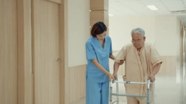 Genç Asyalı kadın hemşire bakıcı desteği, kıdemli hastasına iyi bakmasını tavsiye ediyor. Hastane koğuşunda yürümeyi sürdürüyor. Hastane çevresi kavramı..