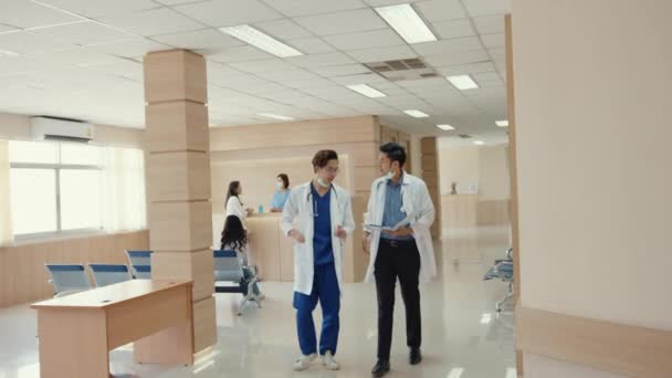 アジアの医師は 病院での患者のケースについて話し合います アジアの男性医療従事者は 患者のケースを相談します 医薬品は 医療報告書を示す代表 病院環境コンセプト — ストック動画