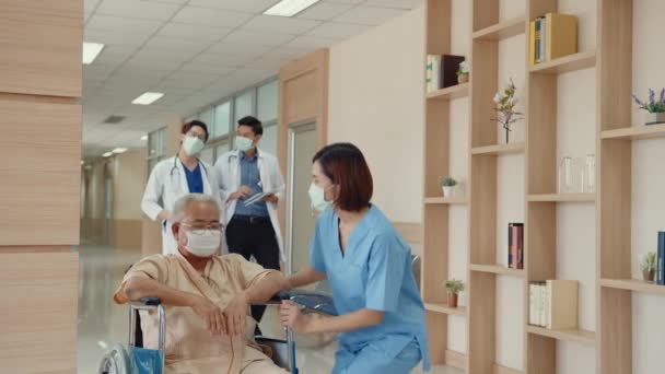 年轻的亚洲女护士护理人员戴着医疗面罩 鼓励照顾病人说明在医院病房使用轮椅的情况 流行病与病毒 医院环境的概念 — 图库视频影像
