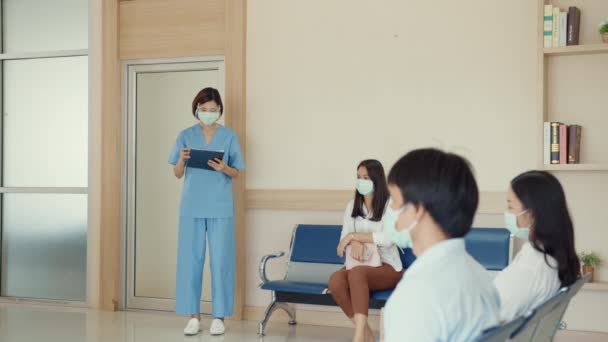마스크를 아시아인 간호사가 대기실에서 환자들을 호출하고 대기실 코로나 바이러스 코로나 — 비디오