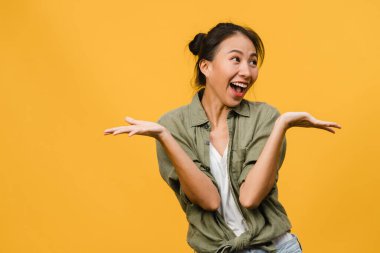 Genç Asyalı bayan mutluluğu olumlu bir ifadeyle hissediyor, neşeli sürpriz funky, sarı arka planda izole edilmiş günlük giysiler içinde. Mutlu, sevimli, mutlu kadın başarıya sevinir. Yüz ifadesi.