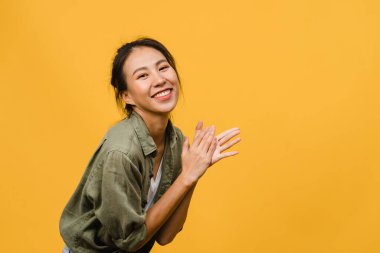 Olumlu ifadeli genç Asyalı bayan, geniş bir gülümseme, günlük kıyafetler giymiş ve sarı arka plandan kameraya bakıyor. Mutlu, sevimli, mutlu kadın başarıya sevinir. Yüz ifadesi kavramı.