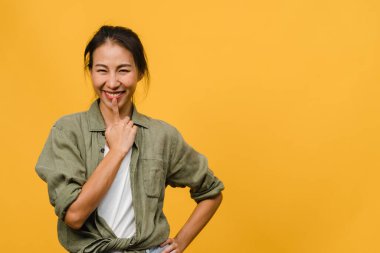Olumlu ifadeli genç Asyalı bayan, geniş bir gülümseme, günlük kıyafetler giymiş ve sarı arka plandan kameraya bakıyor. Mutlu, sevimli, mutlu kadın başarıya sevinir. Yüz ifadesi kavramı.