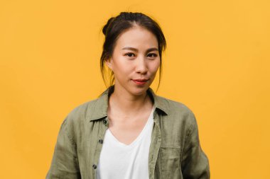 Olumlu ifadeli genç Asyalı bayan, geniş bir gülümseme, günlük kıyafetler giymiş ve sarı arka plandan kameraya bakıyor. Mutlu, sevimli, mutlu kadın başarıya sevinir. Yüz ifadesi kavramı.