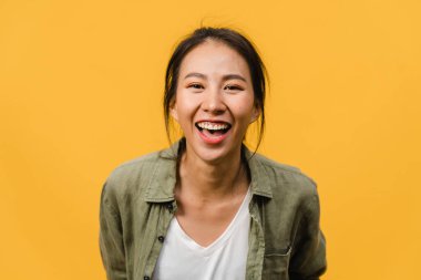 Olumlu ifadeli genç Asyalı bayan, geniş bir gülümseme, günlük kıyafetler giymiş ve sarı arka plandan kameraya bakıyor. Mutlu, sevimli, mutlu kadın başarıya sevinir. Yüz ifadesi kavramı.