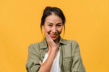 Olumlu ifadeli genç Asyalı bayan, geniş bir gülümseme, günlük kıyafetler giymiş ve sarı arka plandan kameraya bakıyor. Mutlu, sevimli, mutlu kadın başarıya sevinir. Yüz ifadesi kavramı.