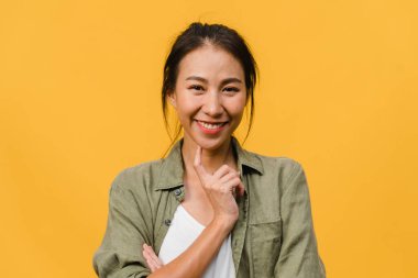 Olumlu ifadeli genç Asyalı bayan, geniş bir gülümseme, günlük kıyafetler giymiş ve sarı arka plandan kameraya bakıyor. Mutlu, sevimli, mutlu kadın başarıya sevinir. Yüz ifadesi kavramı.