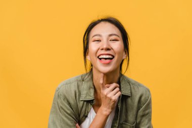 Olumlu ifadeli genç Asyalı bayan, geniş bir gülümseme, günlük kıyafetler giymiş ve sarı arka plandan kameraya bakıyor. Mutlu, sevimli, mutlu kadın başarıya sevinir. Yüz ifadesi kavramı.
