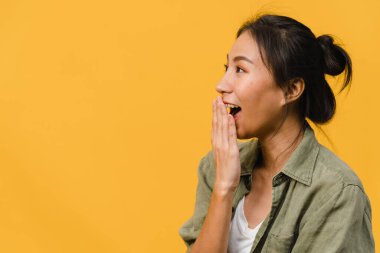 Genç Asyalı bayan mutluluğu olumlu bir ifadeyle hissediyor, neşeli sürpriz funky, sarı arka planda izole edilmiş günlük giysiler içinde. Mutlu, sevimli, mutlu kadın başarıya sevinir. Yüz ifadesi.