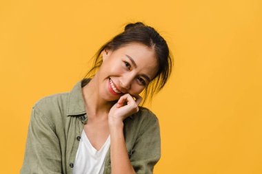 Olumlu ifadeli genç Asyalı bayan, geniş bir gülümseme, günlük kıyafetler giymiş ve sarı arka plandan kameraya bakıyor. Mutlu, sevimli, mutlu kadın başarıya sevinir. Yüz ifadesi kavramı.